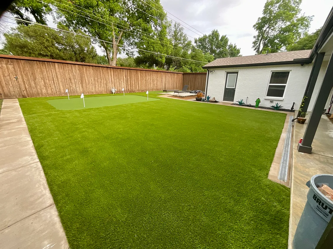 Artificial grass lawn and putting green bordered by a wooden fence